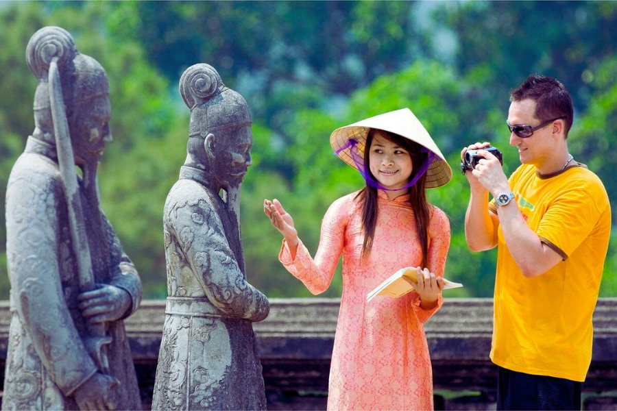 Vietnamese woman in ao dai guiding tourist at historic site in Hue Vietnam